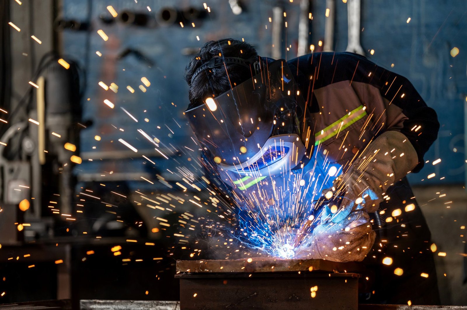 A professional welder working with focus in an industrial manufacturing setting
